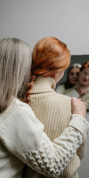 Une mère qui enlace sa fille par l'épaule devant un miroir
